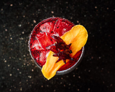 Closeup of red cocktail topped with fruit slice