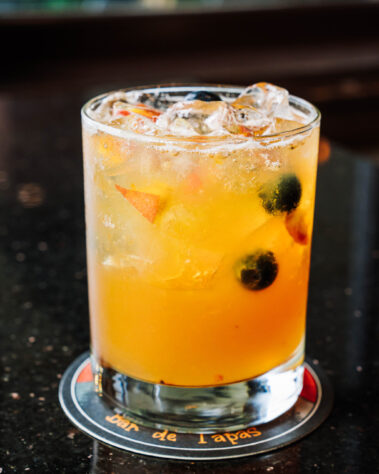 Orange cocktail with pieces of blueberries and other fruit
