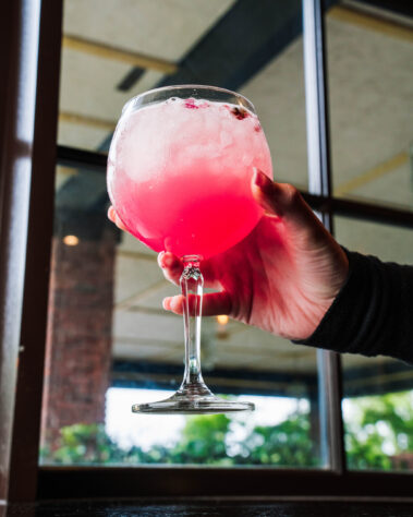 Hand holding up a pink cocktail