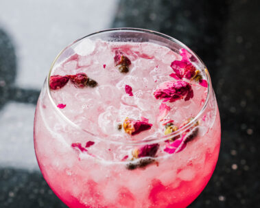 Closeup of pink cocktail topped with dried petals