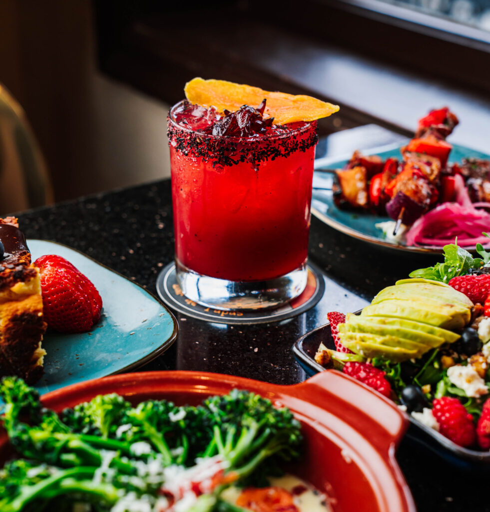 Red cocktail with other food plates out of focus